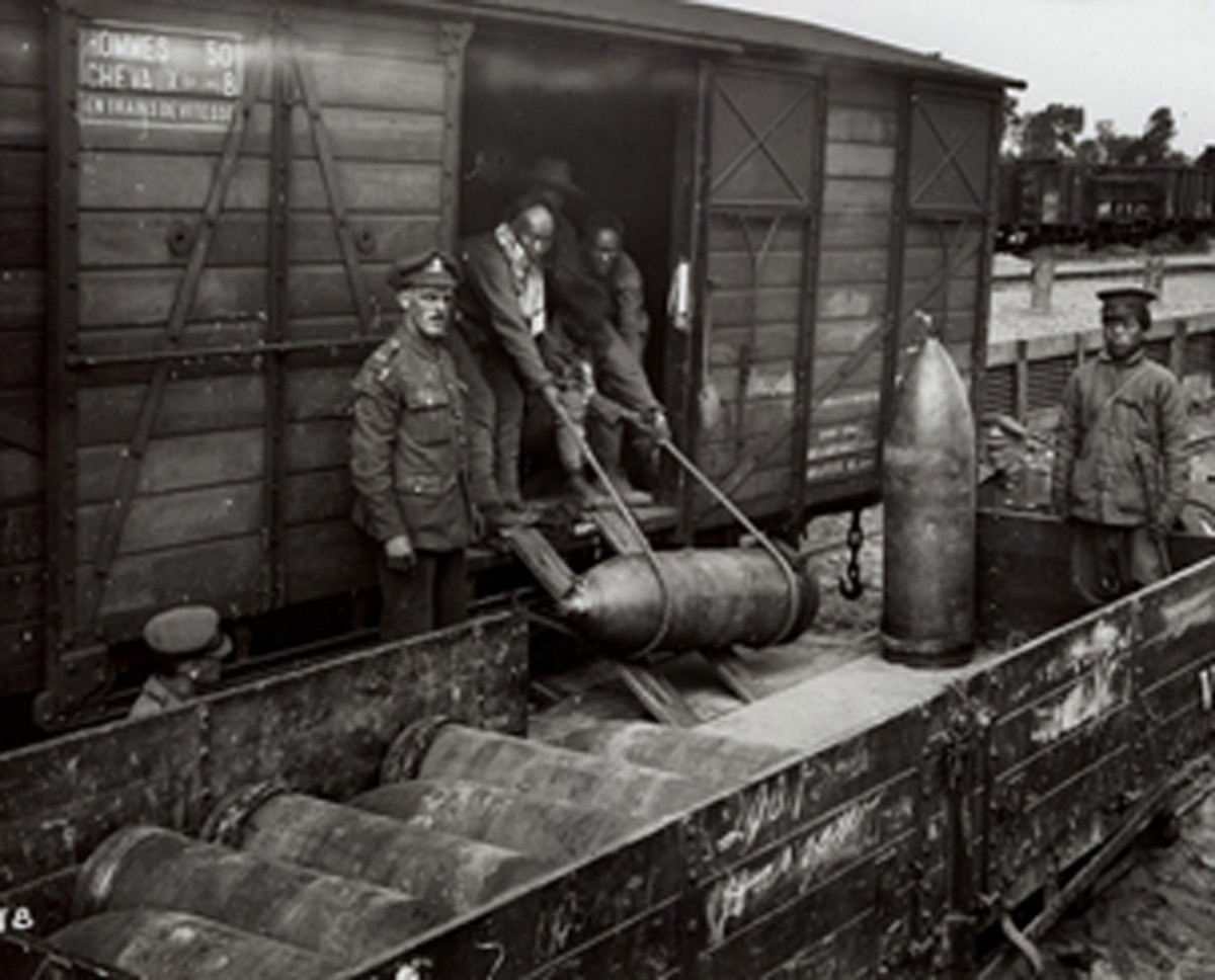 Black and white photograph showing Chineses workers loading a train with shells