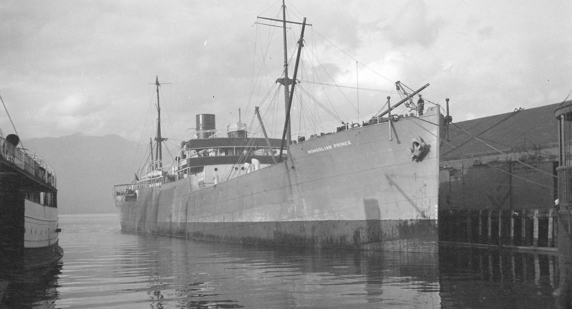 Black and white photograph showing a troopship at dock